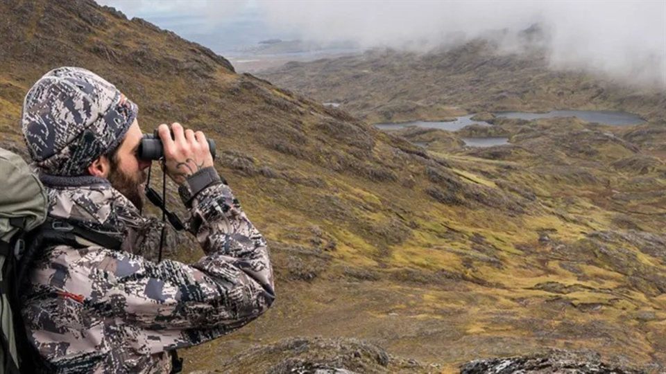 Birdwatcher with binoculars in a mountain landscape