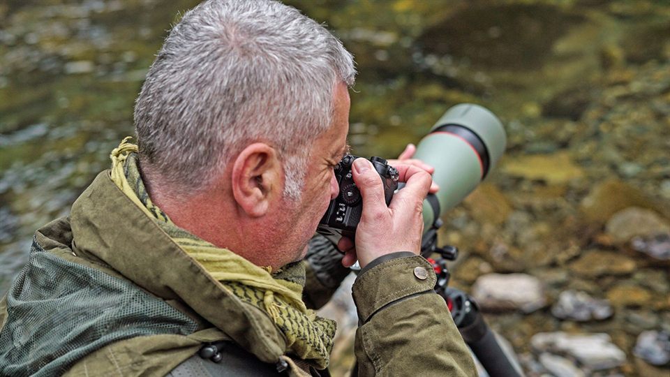 Birdwatcher photographing wildlife beside water